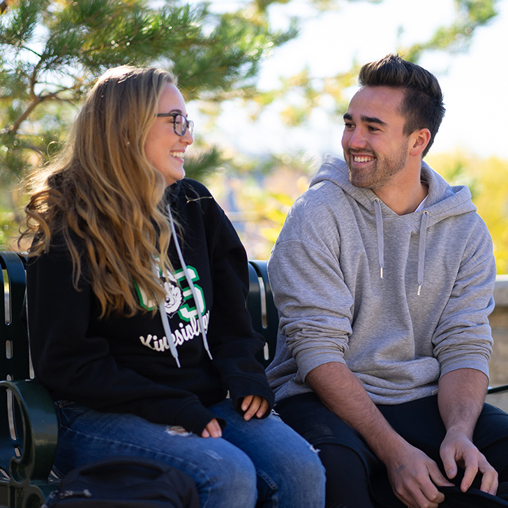 Students sit on bench outside 